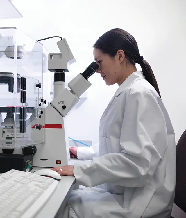 researcher looking through microscope